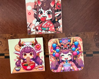 Op de afbeelding: Drie geïllustreerde stickers met anime-achtige personages met dierenoren en hoorns. De eerste sticker toont een personage met bruin haar en rode hoorns dat een rode lolly eet. De tweede sticker toont een personage met paars haar en witte hoorns dat ramennoedels eet. De derde sticker toont een personage met paars haar en rode hoorns dat een boba-thee drinkt.