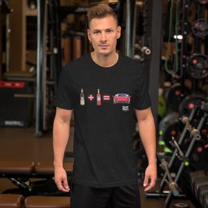 May include: Dark gray t-shirt featuring a graphic of a bottle of wine, a bottle of liquor, and a red sports car with the text "Ec2." The shirt is made of a soft material.