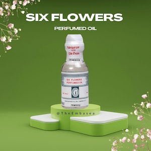 Może przedstawiać: Przezroczysta butelka szklana z białą etykietą z napisem "Six Flowers Perfumed Oil". Butelka stoi na zielono-białej platformie. Butelka została wyprodukowana w Wybrzeżu Kości Słoniowej.