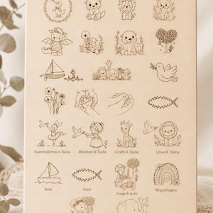 May include: A light-colored wooden board featuring the text Motivauswahl at the top, followed by a grid of various engraved line art illustrations including animals, flowers, a sailboat, a rainbow, and children, with labels in German below some icons.