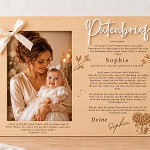 May include: A rectangular wooden plaque featuring a photo frame on the left with a white ribbon bow, and German text on the right including the word Patenbrief, the name Sophie, and dates. The design includes engraved botanical illustrations.