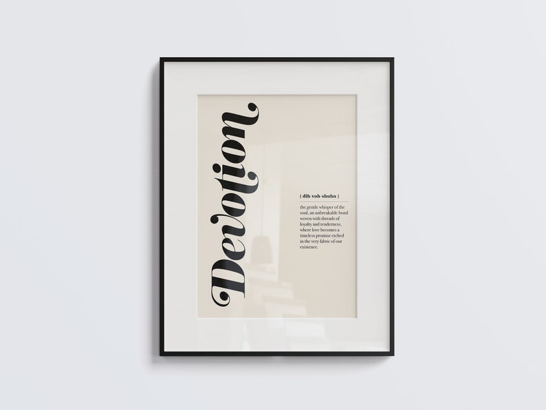 May include: A framed print with a black background and white text. The word "Devotion" is written in a large, stylized font. The definition of the word is written in a smaller font below. The definition reads: "[dih-voh-shuhn] the gentle whisper of the soul, an undeniable bond woven with threads of loyalty and tenderness, where love becomes a timeless promise etched in the very fabric of our existence."