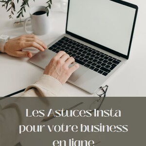 May include: A person working on a laptop computer with a white screen. The laptop is on a white table with a cup of coffee and a plant in the background. The text on the screen reads "Les Astuces Insta pour votre business en ligne Guide".