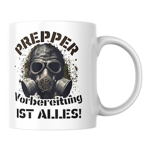 Könnte beinhalten: Weiße Keramiktasse mit einem schwarzen und grünen Gasmasken-Motiv und dem Text "PREPPER Vorbereitung IST ALLES!"