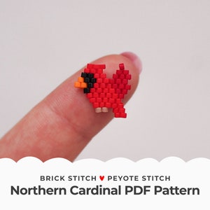 Puede incluir: Un pájaro cardenal rojo, negro y naranja de cuentas, hecho con punto de ladrillo y punto de peyote, se sostiene en un dedo. La imagen es para un patrón PDF descargable para hacer cuentas.