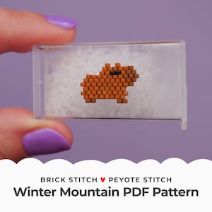 May include: A small, brown and black beaded capybara in a clear plastic container. The container is filled with white beads. The text "BRICK STITCH ♥ PEYOTE STITCH Winter Mountain PDF Pattern" is below the container.