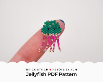 Puede incluir: Un pequeño amuleto de medusa de cuentas verdes y rosas, hecho con punto de ladrillo y punto de peyote. El amuleto es lo suficientemente pequeño como para caber en un dedo.