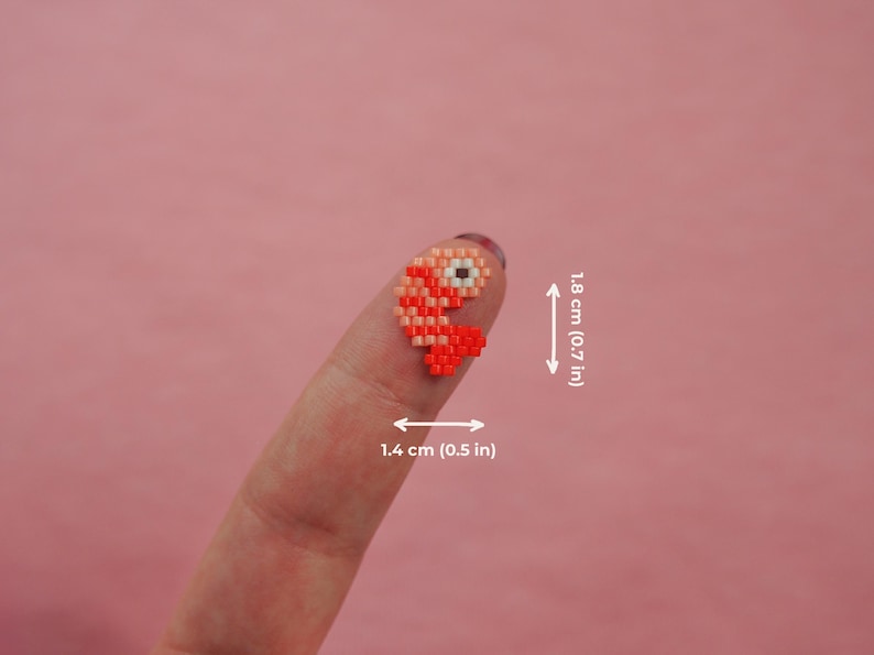Puede incluir: Un peque&ntilde;o pez de cuentas rojo y naranja con un ojo blanco. El pez mide aproximadamente 1,4 cm de ancho y 1,8 cm de alto.