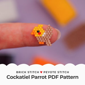 May include: A small, beaded cockatiel parrot in brick stitch and peyote stitch. The parrot is yellow, orange, and brown with black eyes. The parrot is being held by a finger.