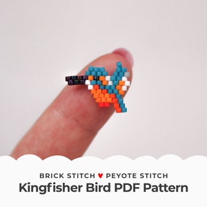May include: A beaded kingfisher bird ring made with brick stitch and peyote stitch. The ring is blue, orange, white, and black.