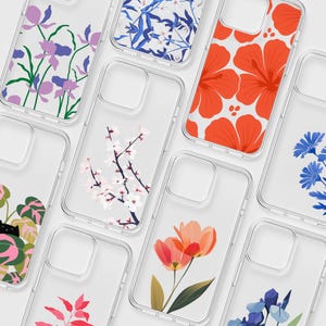 Op de afbeelding: Een collectie doorzichtige telefoonhoesjes met diverse botanische en florale prints, waaronder paarse irissen, blauwe bloempatronen, oranje hibiscusbloemen, roze kersenbloesems, oranje tulpen en een zwarte kat tussen groene en roze bladeren.