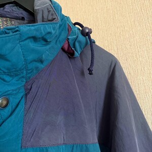 K&ouml;nnte beinhalten: Eine Jacke im Color-Blocking-Design mit Paneelen in Petrol und Dunkelmarineblau. Die Jacke verf&uuml;gt &uuml;ber einen hohen Kragen, eine Kapuze mit dunkelblauem Kordelzug und Stopper sowie einen sichtbaren Metalldruckknopf an der vorderen Knopfleiste.