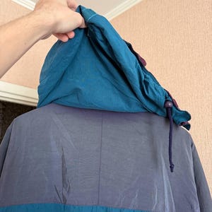 K&ouml;nnte beinhalten: Eine Kapuzenjacke mit Color-Blocking-Design, bestehend aus einer blaugr&uuml;nen Kapuze, einem dunkelgrauen oberen R&uuml;ckenteil und einem blaugr&uuml;nen unteren Bereich. Die Kapuze verf&uuml;gt &uuml;ber einen dunkelblauen Kordelzug mit einem Kunststoff-Stopper.
