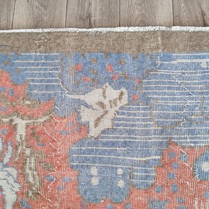 May include: A vintage rug with a blue, pink, and white floral pattern. The rug has a fringe border and is made of wool.