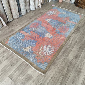 May include: A vintage rug with a blue and pink floral pattern. The rug has a faded, distressed look and is made of wool.