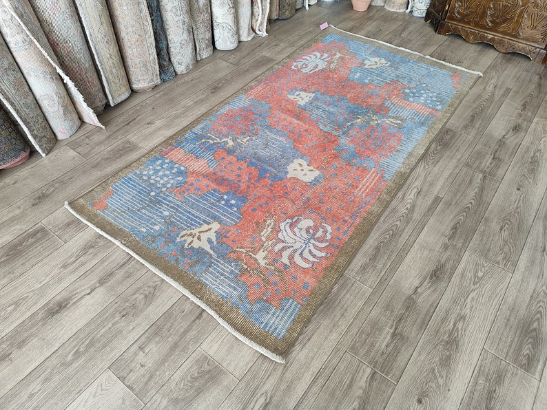 May include: A vintage rug with a blue and pink floral pattern. The rug has a faded, distressed look and is made of wool.