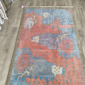 May include: A vintage rug with a floral pattern in shades of pink, blue, and white. The rug has a distressed look and is perfect for adding a touch of vintage charm to any room.