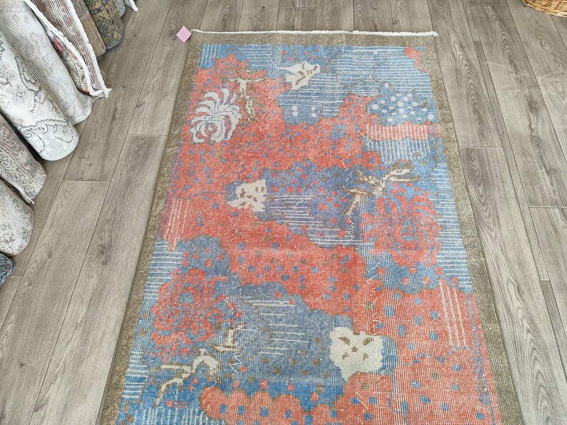 May include: A vintage rug with a floral pattern in shades of pink, blue, and white. The rug has a distressed look and is perfect for adding a touch of vintage charm to any room.