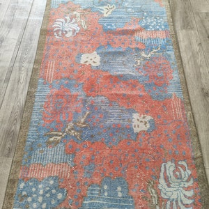May include: A vintage rug with a floral pattern in shades of pink, blue, and white. The rug has a distressed look and is perfect for adding a touch of bohemian style to any room.