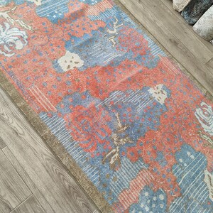 May include: A vintage style rug with a floral pattern in shades of blue, pink, and white. The rug has a distressed look and is perfect for adding a touch of bohemian style to any room.