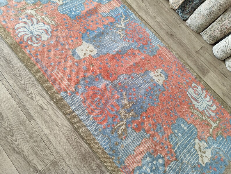 May include: A vintage style rug with a floral pattern in shades of blue, pink, and white. The rug has a distressed look and is perfect for adding a touch of bohemian style to any room.