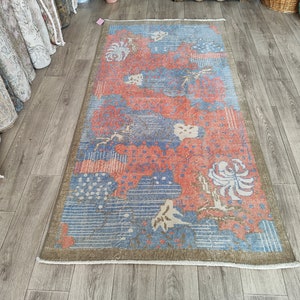 May include: A vintage rug with a floral pattern in shades of blue, red, and white. The rug has a faded, distressed look and is perfect for adding a touch of vintage charm to any room.