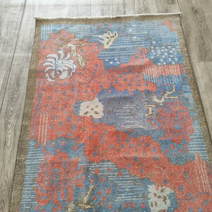 May include: A vintage rug with a blue and red floral pattern. The rug has a faded, distressed look and is made of wool.