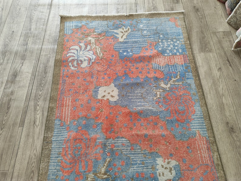 May include: A vintage rug with a blue and red floral pattern. The rug has a faded, distressed look and is made of wool.