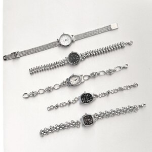 May include: Five silver-toned wristwatches with various band designs and watch faces. The watches have round, oval, and square faces with different dial colors. The bands include mesh, beaded, and chain-link styles. The watches are displayed on a white surface.