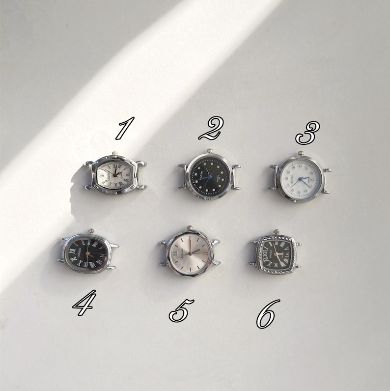 May include: Six small, silver-toned wristwatches with various face designs. The watches have different shapes, including oval and square, and feature Roman numerals and hands. The watch faces are white, black, and silver, with some having a textured appearance.