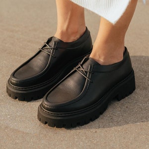 May include: Black leather lace-up shoes with a chunky platform sole.
