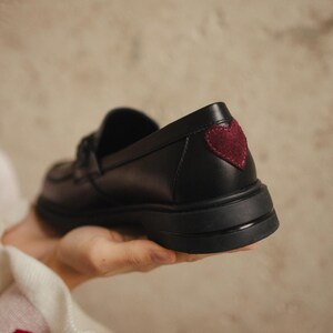 Black leather loafers with red suede heart detail on the back