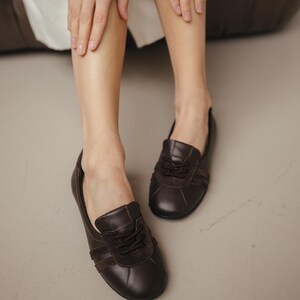 Close-up of handmade brown leather ballet flats with suede inserts, showcasing the sporty sneaker-inspired design and wide rounded toe, against a neutral background