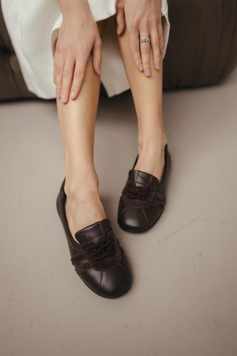 Close-up of handmade brown leather ballet flats with suede inserts, showcasing the sporty sneaker-inspired design and wide rounded toe, against a neutral background