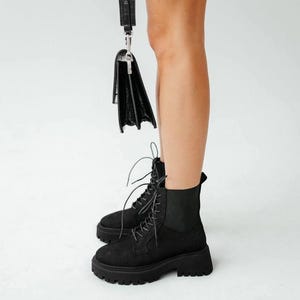 May include: Black suede lace-up ankle boots with a chunky platform sole.