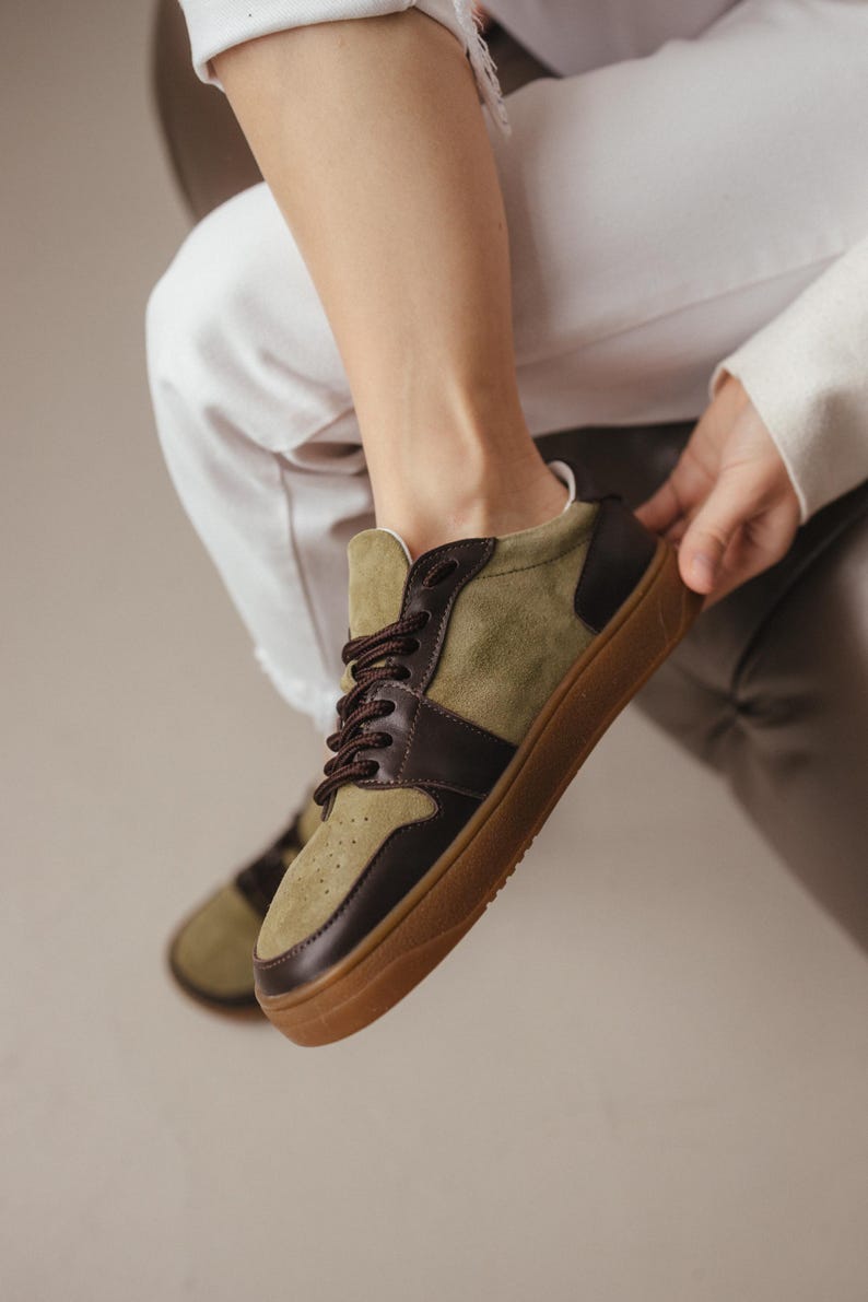 Pair of khaki leather and olive suede sneakers with wide toes, placed on a light gray surface, showcasing the minimalist design and TEP sole