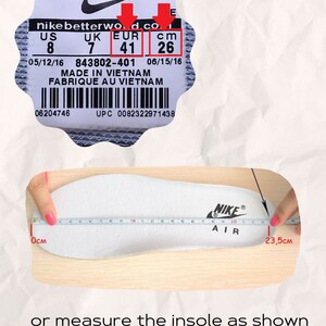 May include: A white shoe insole with the Nike Air logo, measured with a tape showing a length of 23.5 cm. Above, a product label displays size information: US 8, UK 7, EUR 41, and 26 cm. Text reads: Please check your sports shoes to find centimeters and choose the right size or measure the insole as shown in the example.
