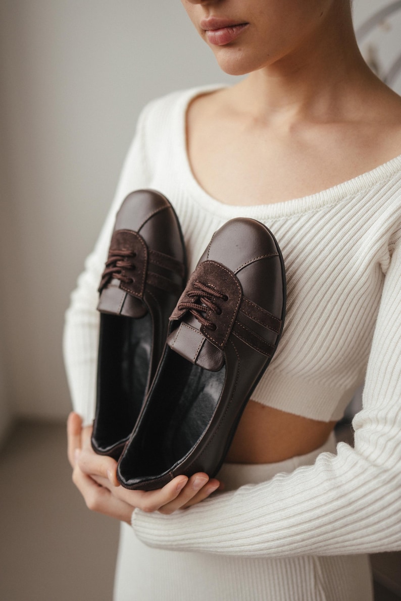 Top-down view of women's brown leather ballet flats with suede inserts, showing the wide toe design and sporty style, on a clean background