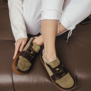 Inside view of handmade sneakers showing the soft natural sheep leather lining, with khaki leather exterior visible, on a clean background