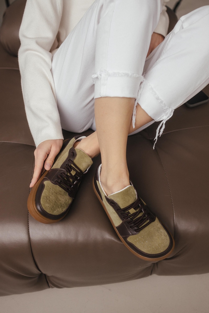 Inside view of handmade sneakers showing the soft natural sheep leather lining, with khaki leather exterior visible, on a clean background