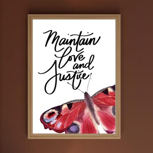 May include: Framed art print featuring a watercolor butterfly with red, purple, and black markings. The print has the words "Maintain Love and Justice" in elegant black script on a white background.