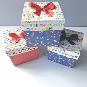 May include: Three colourful gift boxes with different patterns. The top box has a blue background with white stars and confetti, and the text "Happy Birthday! Celebrate Make a Wish!" The middle box has a red background with white polka dots. The bottom box has a blue background with white stars and confetti, and the text "Happy Birthday! Celebrate Make a Wish!"