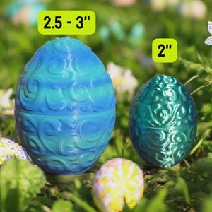 May include: Two decorative Easter eggs, one blue and one green, with ornate swirl patterns. The larger egg measures 2.5-3 inches, and the smaller egg is 2 inches. The eggs are set in a grassy environment with other decorated eggs.