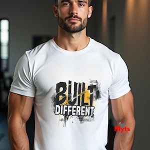 Könnte beinhalten: Weißes T-Shirt mit Rundhalsausschnitt und dem Text "BUILT DIFFERENT" in Schwarz und Gelb. Die Grafik hat ein Distressed-Design mit Farbspritzern. Das kurzärmelige Shirt scheint aus leichtem Material zu sein.