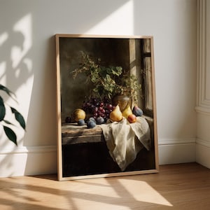 May include: A framed still life painting featuring a wooden table with a collection of fruits. The arrangement includes red grapes, pears, figs, and a peach, alongside a vase of greenery. The artwork is set against a dark background with a window.