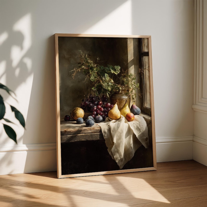May include: A framed still life painting featuring a wooden table with a collection of fruits. The arrangement includes red grapes, pears, figs, and a peach, alongside a vase of greenery. The artwork is set against a dark background with a window.