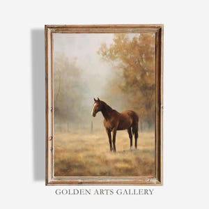 May include: A framed painting of a brown horse standing in a field. The horse has a white stripe on its face. The background features trees and a hazy atmosphere. The frame is a light brown color. The text "GOLDEN ARTS GALLERY" is at the bottom.