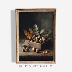 May include: A framed still life painting featuring a wooden box overflowing with acorns, pine cones, and autumn leaves. The artwork has a warm, rustic color palette with a dark background. The text "GOLDEN ARTS GALLERY" is at the bottom.