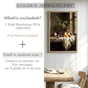 May include: A framed still life print featuring a wooden table with a vase of greenery, grapes, plums, pears, and a draped cloth. The print is in a light wood frame. Text at the top reads "GOLDEN ARTS GALLERY".