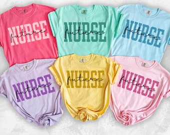 Könnte beinhalten: Sechs kurzärmelige T-Shirts in verschiedenen Farben, darunter Rosa, Blau und Gelb. Jedes Shirt zeigt das Wort "NURSE" in fetten Blockbuchstaben über dem Wort "future" in Schreibschrift. Die Shirts sind mit Farbbezeichnungen versehen.